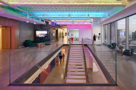 This dynamic stairway landing reveals a flexible lounge space and features modern glass railing with etched artwork of city subway lines and the Arup logo