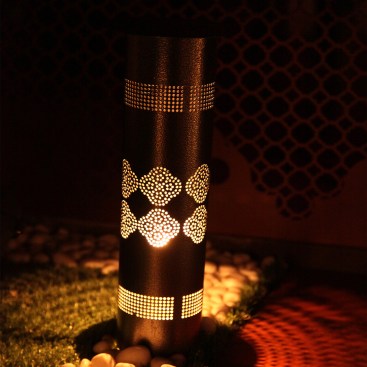 The lamp in a garden area showing the effect of light caused due to the intricate metal cut works.