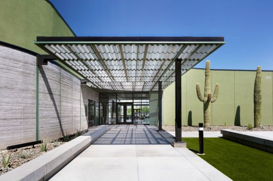 Perforated metal canopies provide much-needed shade outdoors, and create a signature ceiling element inside using texture and layering to blend the interior and exterior space.