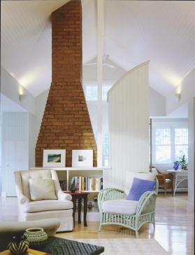 Inside the renovated portion, a curved, freestanding refrigerator cabinet separates the kitchen from the living room.