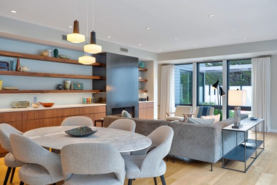 The dining and living space is anchored with a wall of walnut cabinetry and floating shelves to the north.