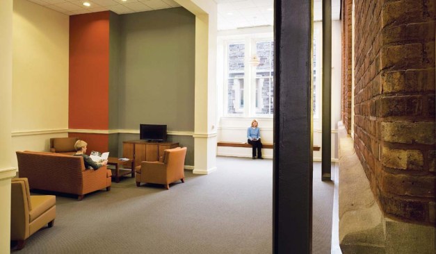A new entrance (opposite), denoted by a glass canopy, is positioned along the fa?ade of the addition, providing an entry close to the heart of campus. When students enter, they can see the old Hunt fa?ades preserved within. Original windows have been converted to display cases for the anthropology department (above left). Steel structural members indicate the perimeter of the self-supporting addition and leave the original fa?ades exposed in lounge areas (above right).