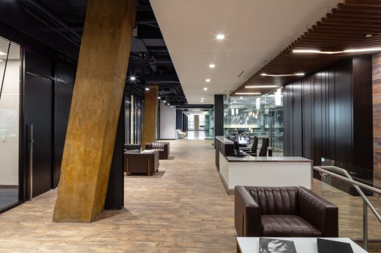 The second floor’s grounded grandeur expresses PN Hoffman’s narrative through layers. The thoroughfare’s partially exposed ductwork ceiling supports its neighboring, hard ceiling and the far right, suspended angled wood-ribbed ceiling – a continuation from the lobby. This texture flows effortlessly beside the high-gloss, vertical metal paneled wall and draws the eye toward the office’s conference center and view of the Potomac.