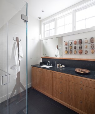 The master bathroom provides additional display space, and continues the vocabulary of cherry and infusion of nature light.