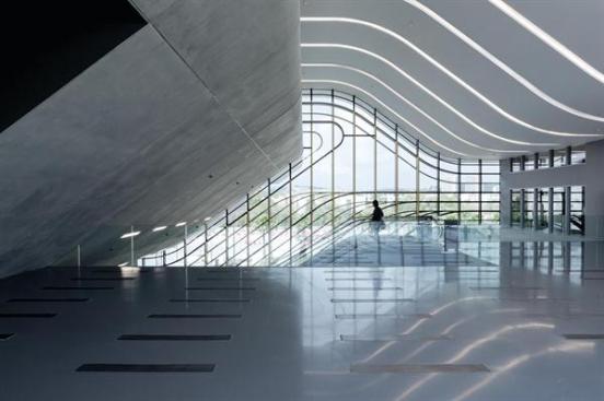 On+the+second+level+of+Pierresvives%2c+a+triple-height+lobby+features+a+curving+roof+incised+with+cove+lighting.