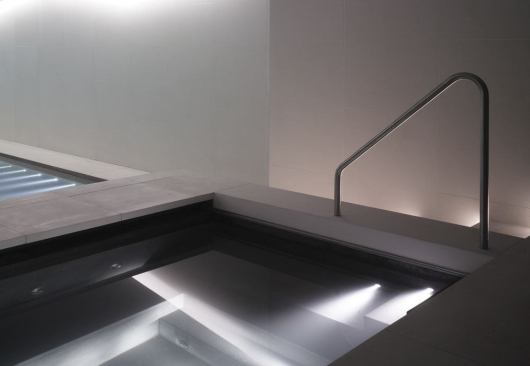 The luxuriously deep Jacuzzi is lit with narrow beam fiber optic steplights, which dramatically skim light across the dark stone, creating impact, defining form, and helping the visitor navigate their footing.
