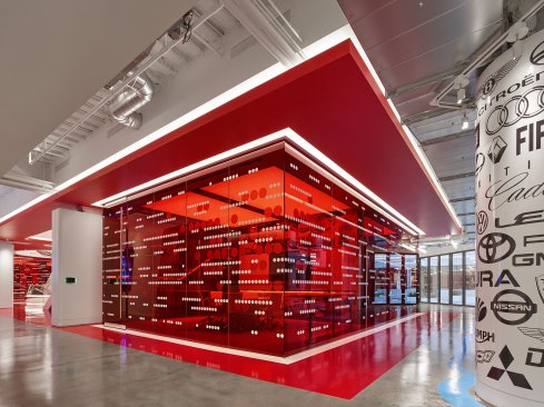 The "stoplight red" conference rooms are illuminated by backlit ceilings, focused downlights, and washes at white boards, while outlined at the perimeter with covelighting.