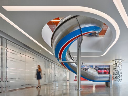 The twisting slide is set off by a curved cove in contrast  to the side light from the glass front of the conference rooms.