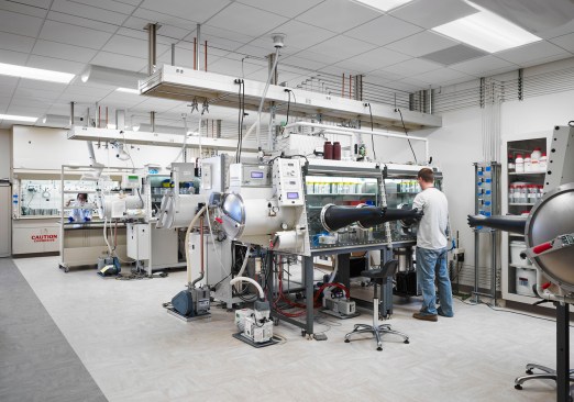 This catalysis lab is fume-hood intensive with glove boxes served from overhead services carriers. There is visibility throughout the lab for safety. Lab coats are not worn by scientists working in these glove boxes because they can create a cross-contamination problem.