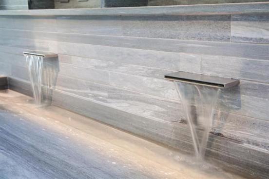 A carved stone lavatory cantilevers from the tiled wall.