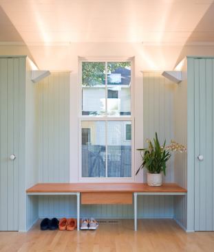 Painted beaded board closets and cabinetry read as furnishings against a backdrop of white plaster walls.