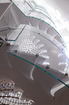 A curved laminated glass balustrade wraps the stair.