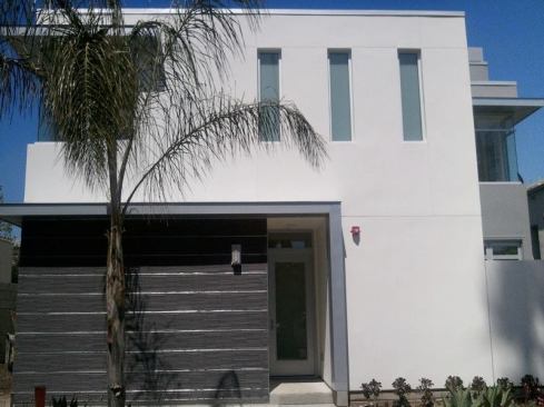 Charcoal-gray Japanese porcelain tiles accent the entry area of the stucco-clad townhouses, which blend high-performance features with coastal elegance.


