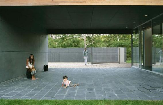 A breezeway provides a transitional space between the gravel covered entryway and the grassy main courtyard. 