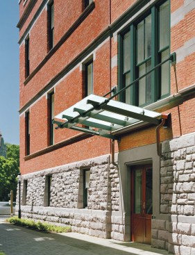 A new entrance (opposite), denoted by a glass canopy, is positioned along the fa?ade of the addition, providing an entry close to the heart of campus. When students enter, they can see the old Hunt fa?ades preserved within. Original windows have been converted to display cases for the anthropology department (above left). Steel structural members indicate the perimeter of the self-supporting addition and leave the original fa?ades exposed in lounge areas (above right).