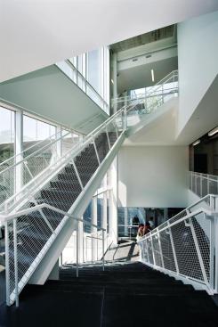 Interior circulation centers on a series of stairs on the west side of the building. The first flight mirrors an outdoor staircase, which doubles as seating for performances. Standing on the second floor landing, students can see up into a courtyard on the third floor.