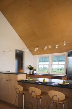 An upside-down layout locates daytime spaces at the second floor, with views over the surrounding vegetation.