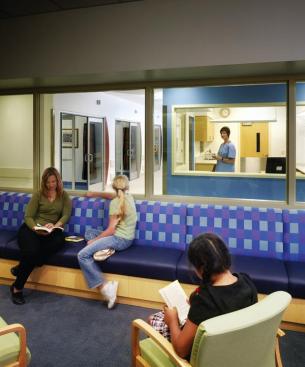 Glass walls in the pediatric pre-op area allow transparency between the family waiting room, nurses station, and staging rooms, allowing visual communication and reducing anxiety. Upholstery: Designtex; Block Party upholstery fabric; designtex.com - Upholstery: Paul Brayton Designs; Almost Natural upholstery in 924 Tyrian; paulbraytondesigns.com - Laminate: Wilsonart; Wilsonart Contract Collection high-pressure laminate in Fusion Maple; wilsonart.com