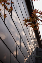 The metal roof and wall tiles were set in a horizontally oriented, staggered pattern that resembles the prior brickwork base and wood-clad siding.