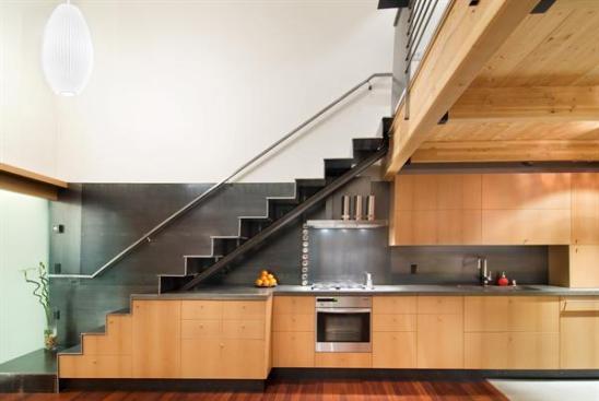 The metal stair leads from the second floor main living space to a reading loft. Custom cabinetry throughout the home stores kitchen and laundry supplies, as well as other secrets.