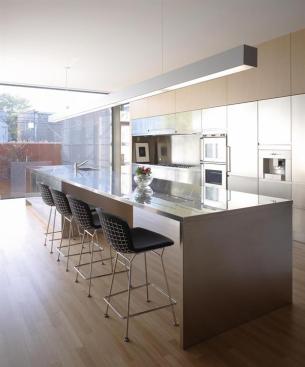 A stainless steel island and a matching bank of cabinets define the combined kitchen and dining area.