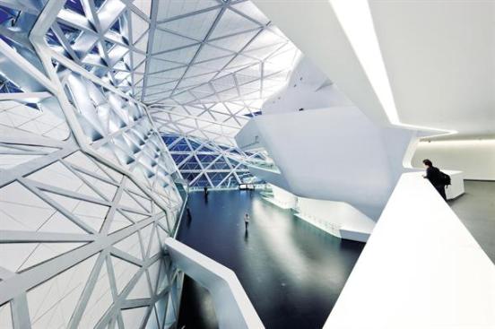 Balconies and staircases hang off the concrete structure of the main theater. Wall and ceiling panels set into the structural steel lattice follow the same triangular geometry as the granite panels do on the exterior.