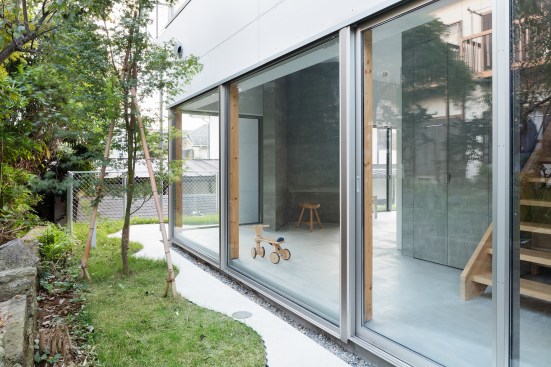 a narrow garden space surrounds the home, with an apron of undulating concrete  extending the interior 