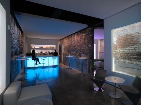 In Salon C the service bar's backlit glass detail is identical to the entry wall. The bottle shelves are incorporated into the wall. Warm-white LED fixtures fit within the small niche provided and generate minimal heat. A pair of floating gypsum frames flanks the front sitting area.