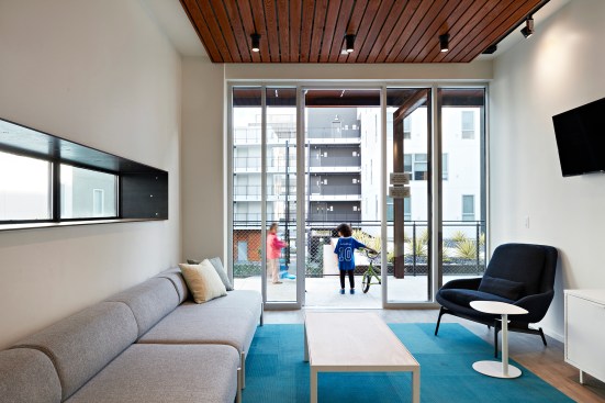 A second-floor lounge opens onto an open-air walkway, one of several community spaces in the building’s internal courtyard.