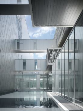 Shallow pools along the ground plane reflect dappled light into the adjacent spaces. 