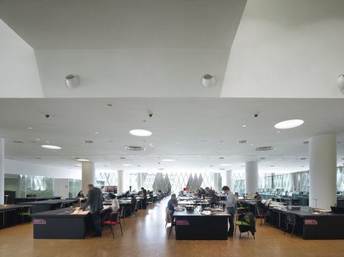 The ground-floor reading room features rows of black tables, where scholars can view archival material. 