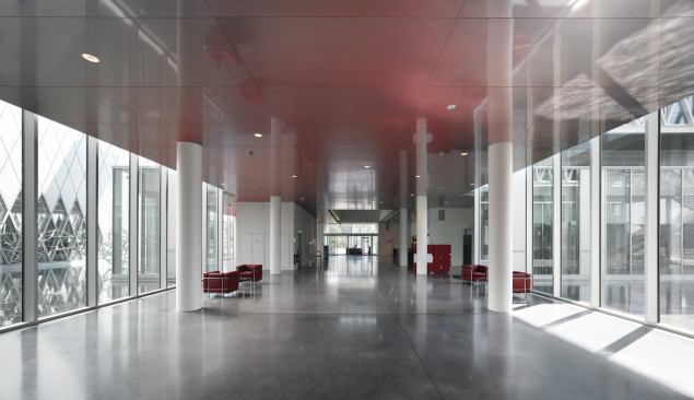 Inside the glazed structure, polished floors and metal ceilings also reflect light deep into the floor plate. Corridors offer sight lines through the building, here, to the public entry.