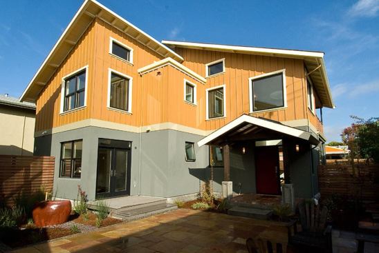 The off-street entrances of the two homes face each other across a private central courtyard. A rain chain provides irrigation for the flower bed next to the covered entryway.