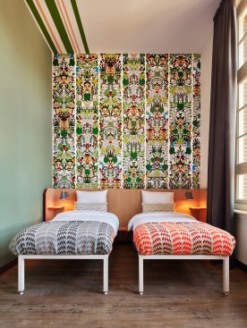 A typical guestroom; each is accented with a Studio Job wallpaper feature wall and gray and brass Anglepoise bedside lamps.
