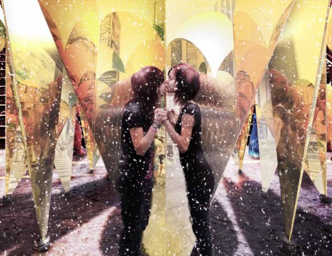 A couple utilizing one of nine "kissing booths," formed by two angled mirrors facing each other but leaving an open gap for people to step into.