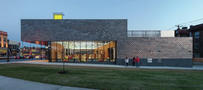 A butt-glazed curtainwall, seen here from the north, wraps the reading rooms. Articulated mullion caps create a balustrade effect.