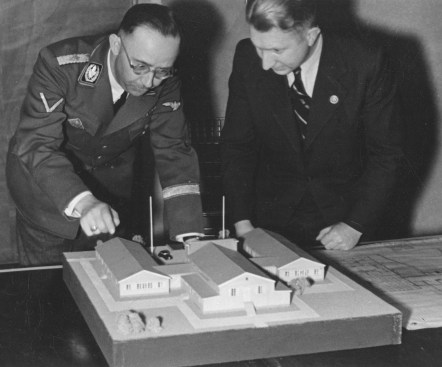 Undated photograph of Heinrich Himmler (left) and Edgar Haller reviewing a model of a home for soldiers, with a building plan beside it. Haller oversaw the construction of soldiers’ homes in occupied Norway.
