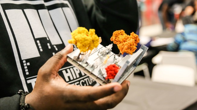 Michael Ford holds a model depicting a cafe with outdoor seating completed by one of the students.