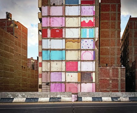 An architectural victim of highway expansion: a literal section-cut exposes what had been interior rooms, expressing the colorful hidden lives of former residents.