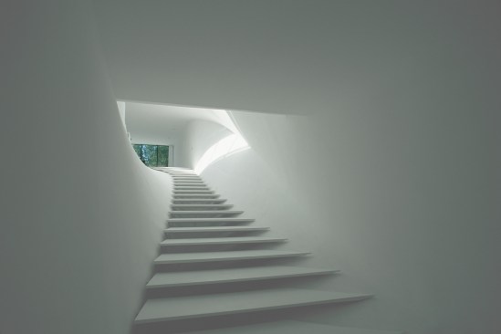 The entry stair from the ground floor to the living space, with treads made from DuPont Corian, ends in a view through a window wall from Hope’s Windows. 