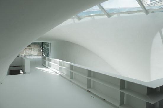 In the second-floor living area, white walls coated in paint from Farrow & Ball arch over a floor made from DuPont Corian in glacier white.