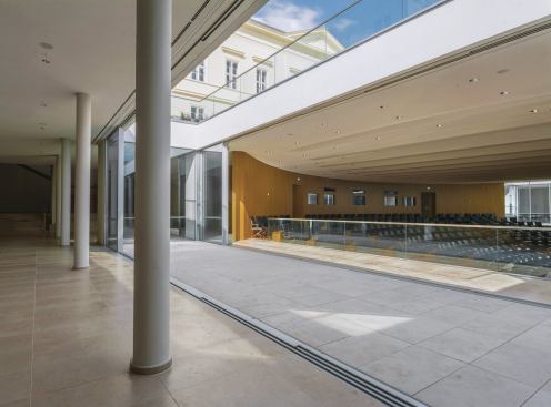 An entirely new below-grade level accommodates a large auditorium and additional seminar rooms. More contemporary than the interiors of the schloss proper, this level is illuminated and ventilated by two atriums cut into the main palace courtyard. Sliding doors connect these open-air spaces to the interiors.