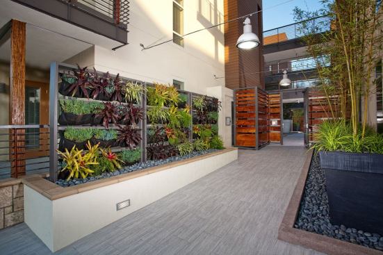 The courtyard features a linear fountain, a living green wall, an outdoor fireplace, barbecue grills, and a community garden.