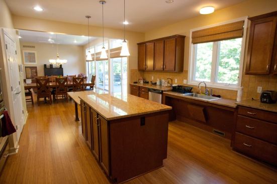 The accessible kitchen features a roll-under sink and dual-height island as well as GE Energy Star-rated appliances and FSC-certified Aristokraft cabinets.