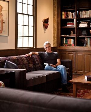 Glass relaxes in the living room. The space's high ceilings and generous windows convey a sense of well-being.