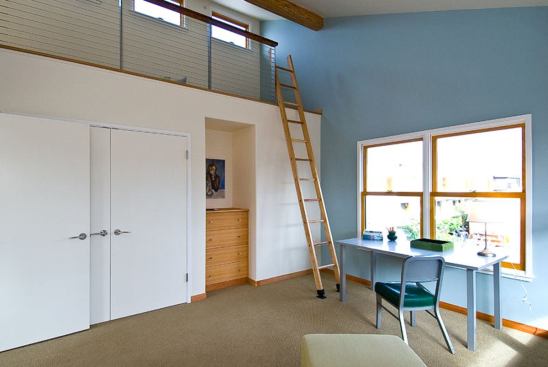 A loft maximizes space in the high-ceilinged second-floor bedroom. The high north-facing windows in the loft bring in natural light and ventilation.