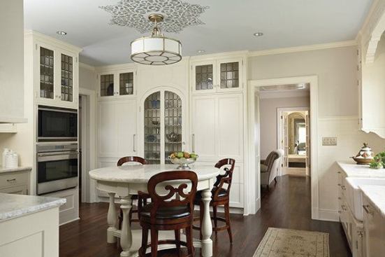 Attention to detail enhances the first-floor kitchen. According to the architects, the room has a circular motif with a round table topped with the same natural iceberg quartzite as the perimeter countertops, and "other period touches include the art-glass doors and ceiling stencil."