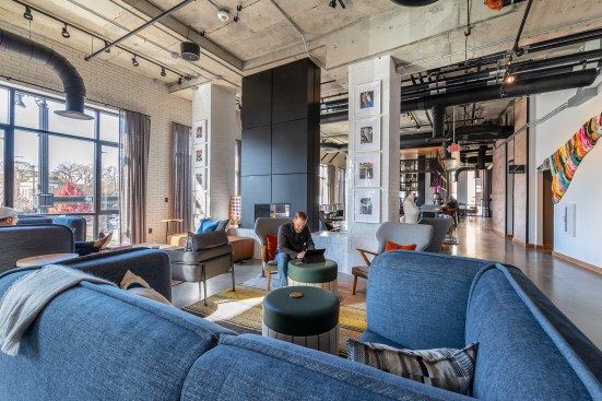 Celano Design Studio specified denim and suiting-inspired fabrics for many of the lobby furnishings to nod to the area's fashion industry history. Exposed mechanical systems and floor-to-ceiling windows add an industrial feel to the space.