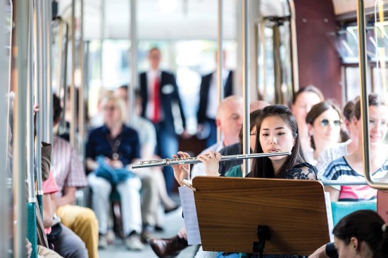 A flutist performing on a city tram