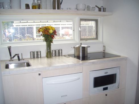 Windows above the kitchen naturally light the work area. Appliances include Whirlpool’s 28-inch white-on-white refrigerator, KitchenAid’s Architect II drawer dishwasher, and Wolf’s 30-inch induction cooktop.
